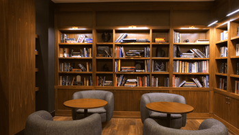 A room with a bookshelf and two grey chairs.